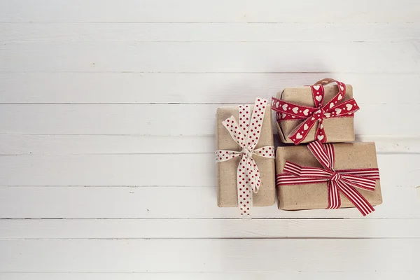 Cajas de regalo con cintas rojas sobre fondo de madera pintado blanco — Foto de Stock