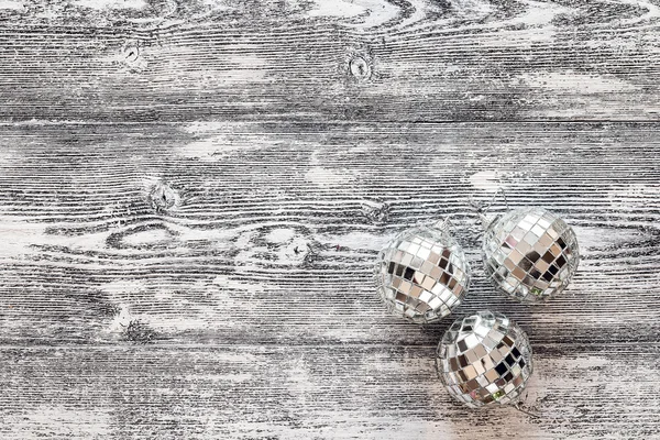 Background with mirror Christmas balls on gray wooden boards.