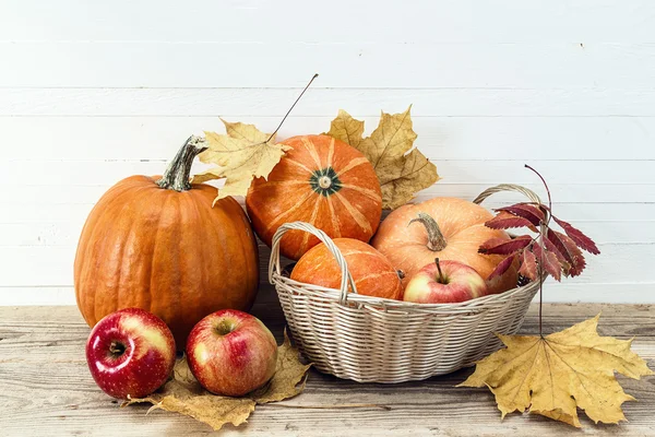 Still life with pumpkins and apples in the basket and autumn lea — Stock Photo, Image