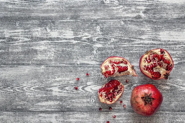 Fresh juicy pomegranate - whole and cut on a wooden grey backgro — Stock Photo, Image