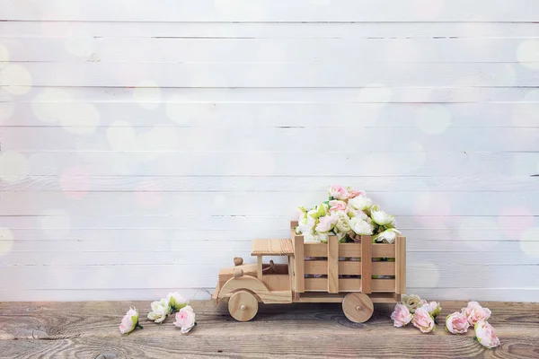 Camion giocattolo in legno con piccoli fiori rose nella parte posteriore su un bianco — Foto Stock