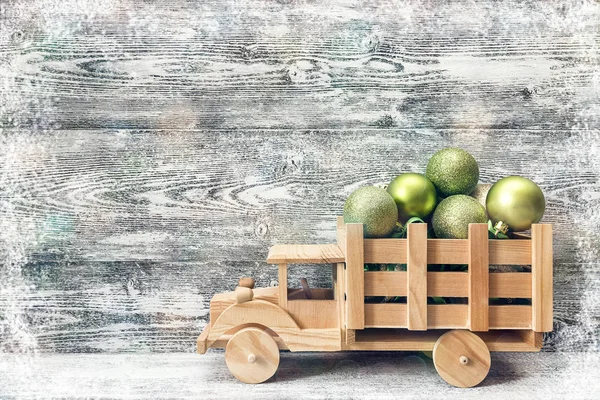 Wooden toy truck with a green Christmas balls in the back on a g — Stock Photo, Image
