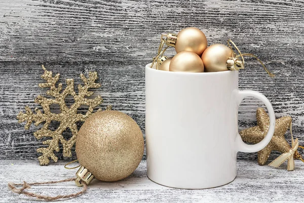 White coffee mug with gold shiny Christmas decorations. Space fo