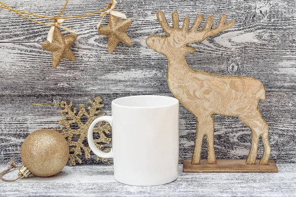 White coffee mug with gold shiny Christmas decorations. Space fo