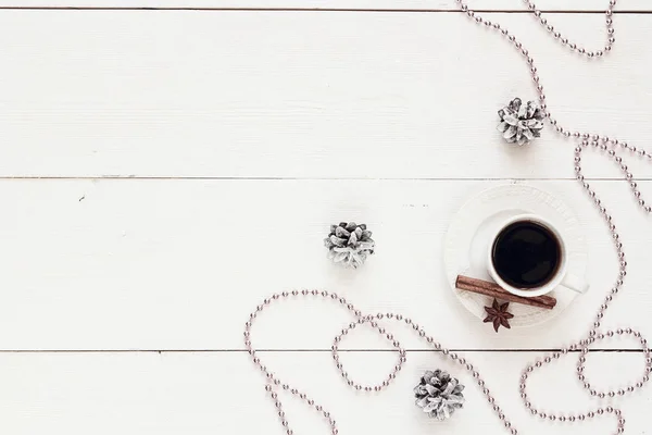 Cangkir kopi putih dengan rempah-rempah, kerucut pinus dan manik-manik Natal — Stok Foto