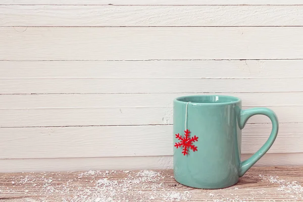 Tasse à thé de Noël bleue avec flocon de neige rouge sur table en bois . — Photo