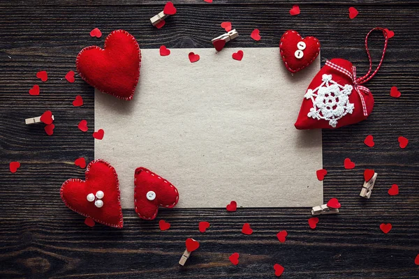 Folha em branco de papel marrom com corações vermelhos na mesa de madeira velha . — Fotografia de Stock