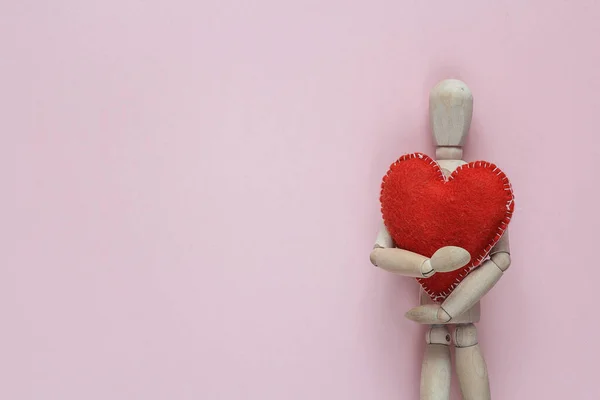 Classic wooden dummy holds red heart for Valentine's Day on a pi — Stock Photo, Image