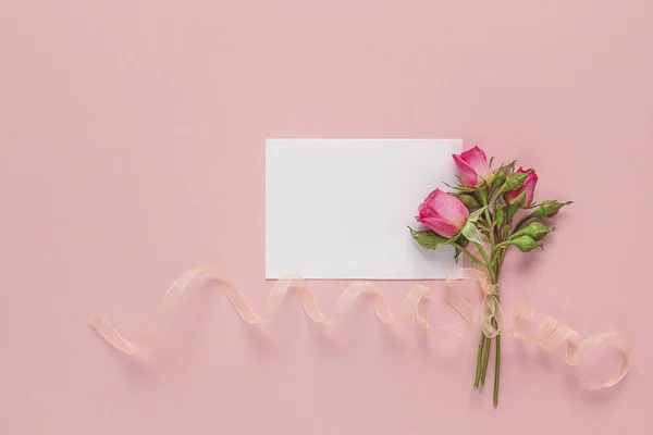 Μικρό μπουκέτο τριαντάφυλλα με κορδέλα και μια κάρτα κενό χαρτί για ένα p — Φωτογραφία Αρχείου