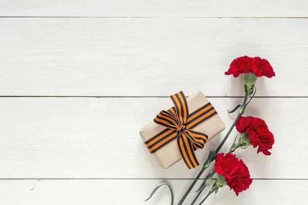 Día del Defensor de la Patria. Claveles rojos y caja de regalo con — Foto de Stock