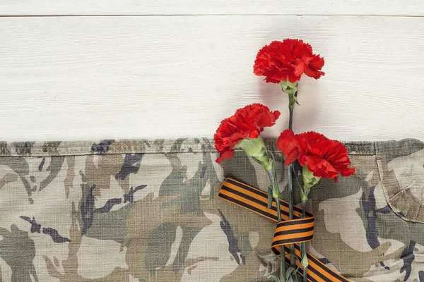 Red carnations with st george ribbons on the khaki background.