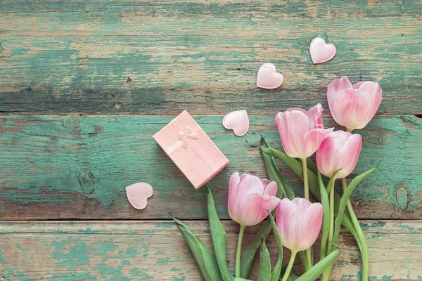 Tulipanes rosados, corazones y caja de regalo en una ba de madera grunge turquesa — Foto de Stock