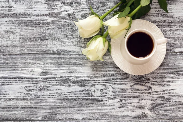 Cangkir kopi dan bunga mawar putih dengan latar belakang meja kayu. Untuk — Stok Foto