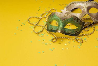Karnaval maskeleri ve boncuklar sarı bir arka plan üzerinde. Metin için yer.