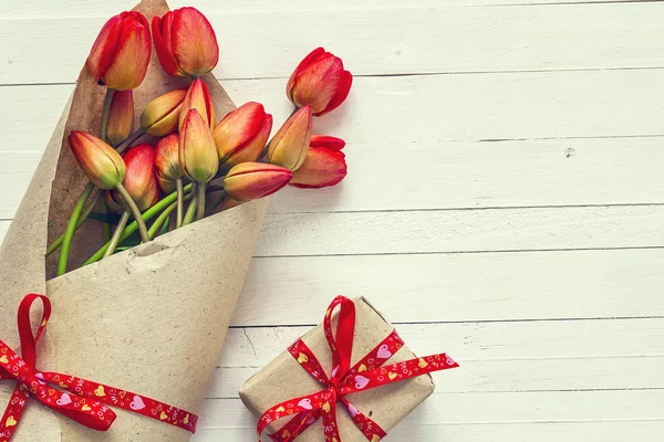 Tulipani rossi e confezione regalo con nastro rosso su legno verniciato bianco — Foto Stock