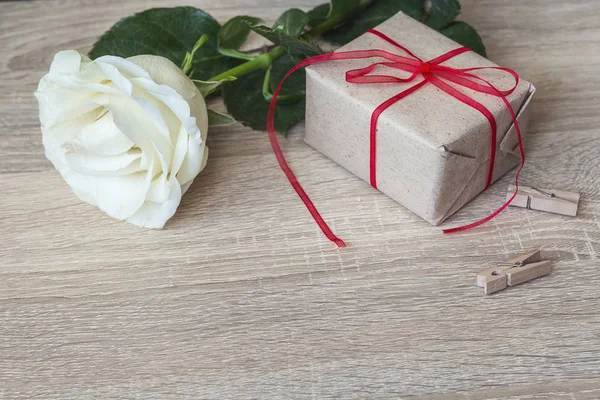 Scatola regalo legata con nastro rosso, rosa bianca su fondo legno . — Foto Stock