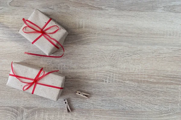 Dos cajas de regalo con cintas rojas, dos pinzas de tela sobre fondo de madera — Foto de Stock
