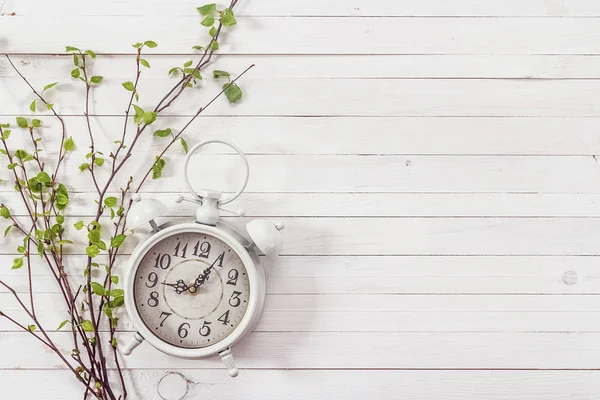 Background with white alarm clock and spring branch on white pai — Stock Photo, Image