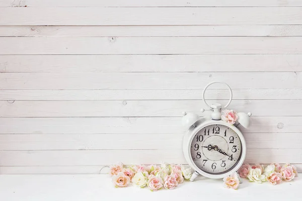 Background with white alarm clock and small pink roses on white — Stock Photo, Image