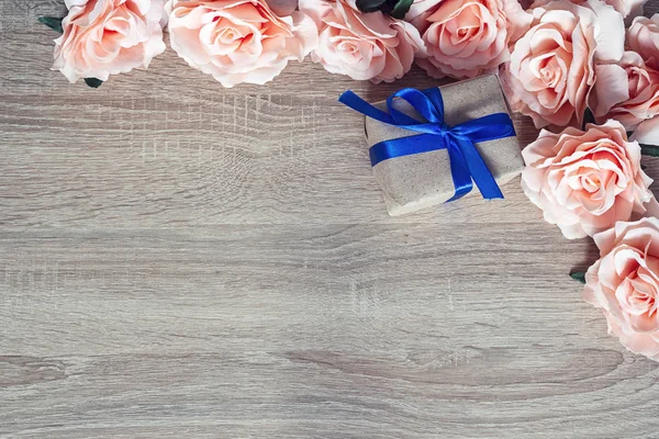 Marco de rosas rosadas sobre un fondo de madera con caja de regalo y emp —  Fotos de Stock