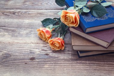 Turuncu gül ve eski ahşap kurullarında kitapların bir yığınına. Kopya spa