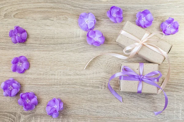 Two gift boxes, purple flowers on wood background with empty spa