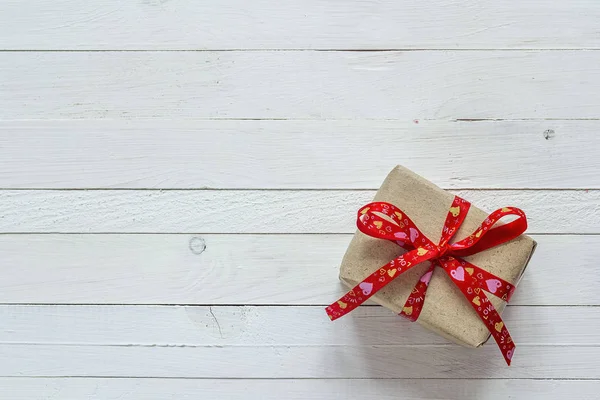 Caja de regalo con cinta roja sobre tablones de madera pintados de blanco y empate — Foto de Stock