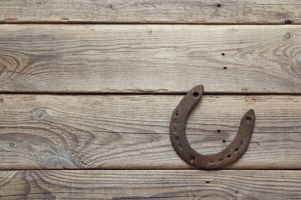 Rusty horseshoe on old wooden board. 