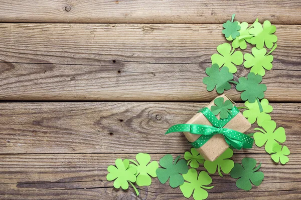 Coffret cadeau avec feuilles de trèfle en papier sur le vieux fond en bois . — Photo