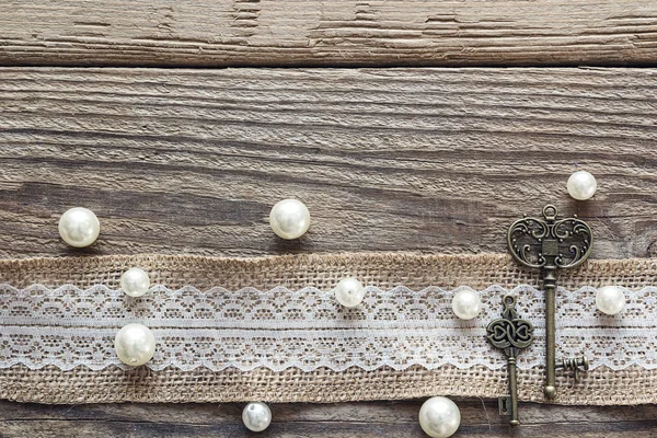 Bordure de toile de jute avec dentelle blanche, clés vintage et perles sur vieux — Photo