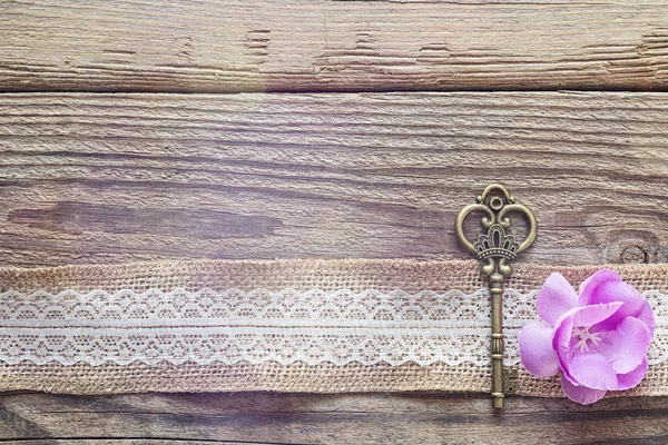 Bordure de toile de jute avec dentelle blanche, clé vintage et fleur violette — Photo