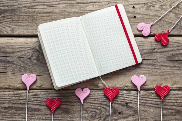 Open blank notebook with hearts on a old wooden background. Spac