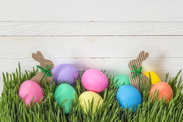 Uova di Pasqua in erba fresca verde su sfondo di legno bianco . — Foto Stock