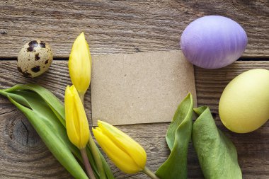 Boş kahverengi kart, Paskalya yumurtaları ve laleler eski bir ahşap tablo. 