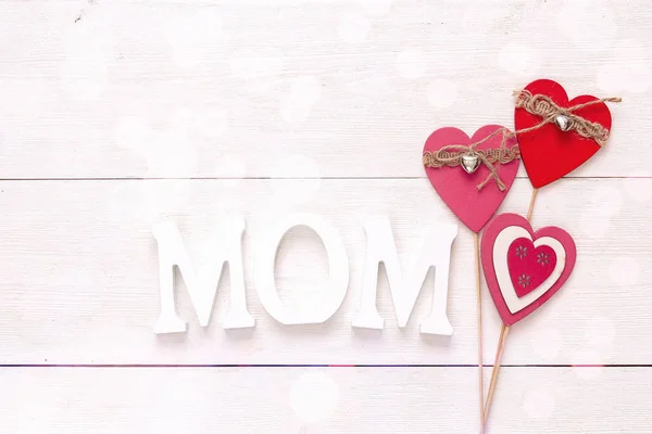 Mothers day message with decorative hearts on a white wooden bac