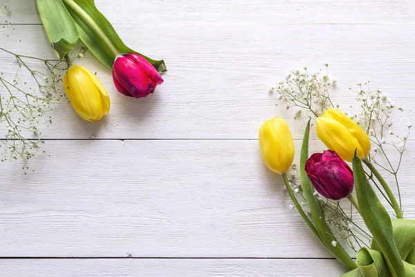 Background with tulips on white wooden table. Space for text.