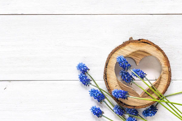 Coeur en bois sculpté avec des fleurs musquées bleues sur bois blanc — Photo