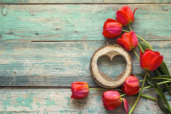 Achtergrond met rode tulpen en houten harten op oude houten bord — Stockfoto