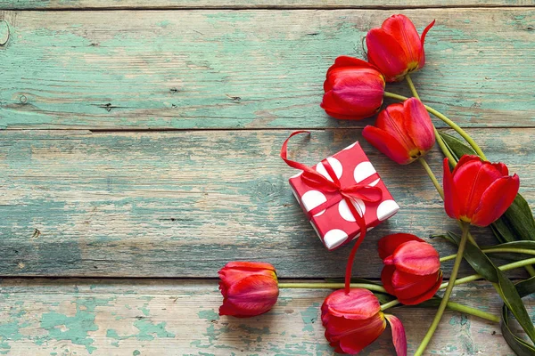 Sfondo con tulipani rossi e confezione regalo su vecchie tavole di legno. Pl — Foto Stock