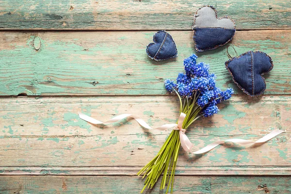 Fleurs de muscari bleu avec des coeurs de jeans sur un vieux fond en bois . — Photo