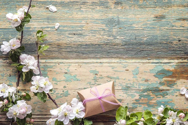 Bloeiende takken van apple met de doos van de gift op houten pagina — Stockfoto