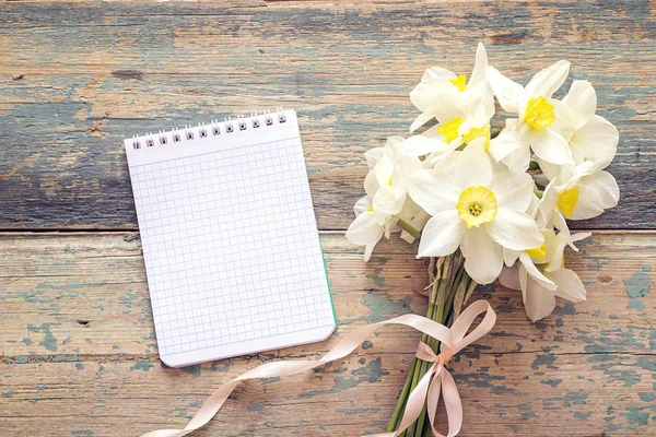 Buquê de flores narcisos com caderno aberto em branco em madeira — Fotografia de Stock