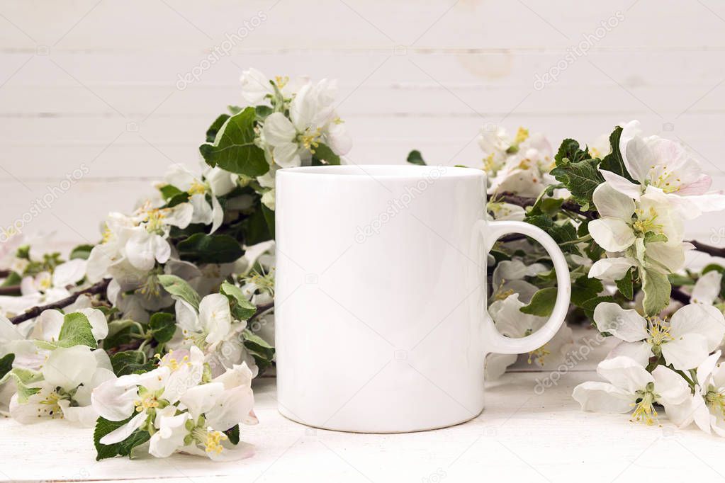 White coffee mug with blossoming apple tree branches. 