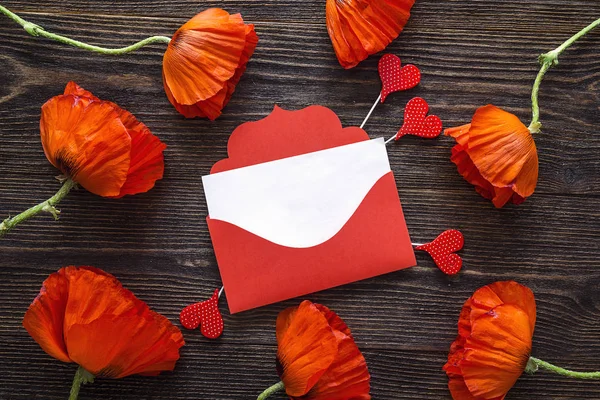 Red envelope with decorative hearts and red poppies flowers on d