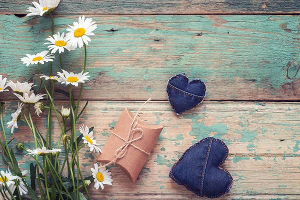 Ramo de margaritas con caja de regalo y corazones de mezclilla en madera vieja — Foto de Stock