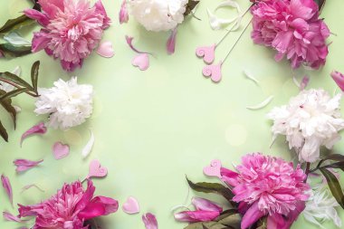 Çerçeve peonies ve yeşil zemin üzerine dekoratif kalpler. TABA