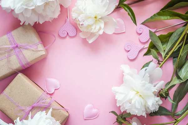 Peonie bianche con scatole di regalo e cuori decorativi su un rosa — Foto Stock