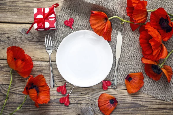 Romantic table setting with cutlery and red poppies on rustic wo
