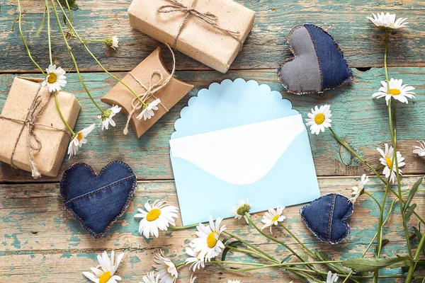 Blue envelope with chamomiles and gift boxes. Space for text. — Stock Photo, Image