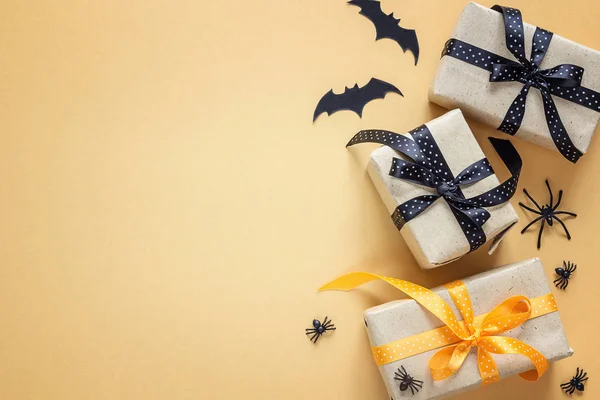 Gift boxes with decorative spiders and bats on orange background